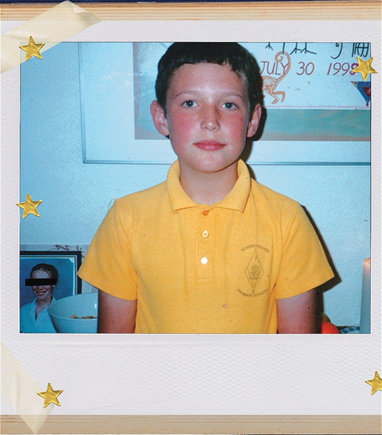 Performer Colin Ebsworth as a child on a polaroid photograph, taped to a table and covered in some gold star stickers. Colin is dressed in a yellow school polo shirt and is standing in front of a religious offering table.