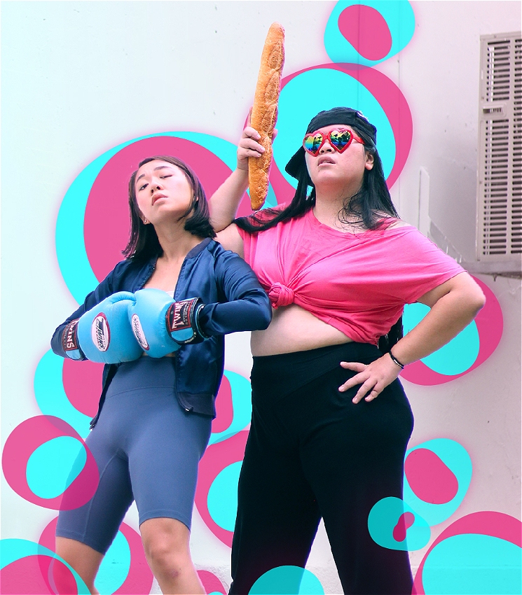 Miriam and Shannen stand side by side, a white wall in the background. They are surrounded by multiple circles of various sizes in cyan blue and hot pink. 
Miriam is a Chinese woman with long black hair and is wearing heart shaped sunglasses, a backwards cap, a hot pink crop top and black pants while holding a baguette loaf erect. Shannen is a Chinese woman with short brown hair and is wearing a white tube top, a blue jacket, grey-blue bicycle shorts and bright blue boxing gloves.