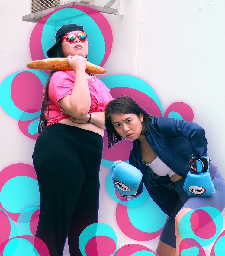 Miriam and Shannen are posed side by side, a white wall in the background. Miriam is standing upright while Shannen crouches. They are surrounded by multiple circles of various sizes in cyan blue and hot pink. 
Miriam is a Chinese woman with long black hair and is wearing heart shaped sunglasses, a backwards cap, a hot pink crop top and black pants while holding a baguette loaf horizontally. Shannen is a Chinese woman with short brown hair and is wearing a white tube top, a blue jacket, grey-blue bicycle shorts and bright blue boxing gloves.