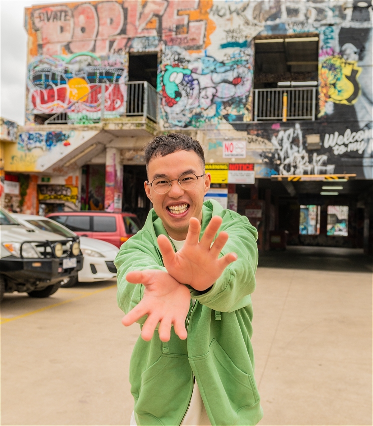 Photo of Comedian Henry Yan doing Kamehameha in car park with Graffiti on the background walls.