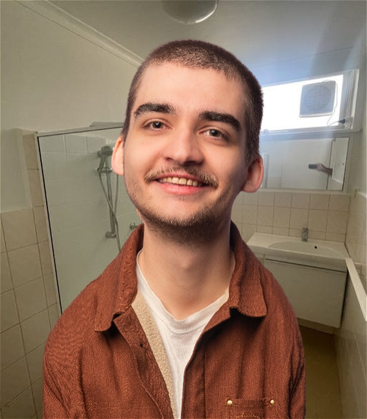 a slightly uncanny man with a buzzcut and light facial hair. His head has been edited to be slightly larger. He is wearing a red rust shirt jacket and is situated in the real estate picture for his bathroom.