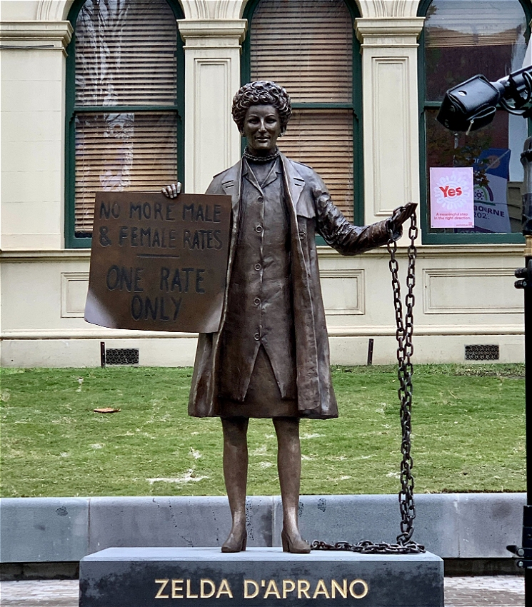 A bronze statue depicting Zelda D'Aprano holding a sign that reads 