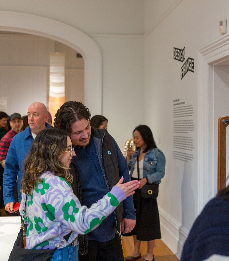In a gallery, two people discuss an artwork out of frame