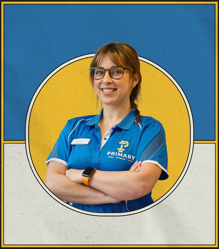 The image shows a woman with light brown hair, glasses, and a friendly smile. She is wearing a blue polo shirt with a 'Primary Fitness' logo and has her arms crossed. The background is divided into blue and yellow sections, with a circular frame highlighting her. She also wears an orange-strap smartwatch on her wrist.