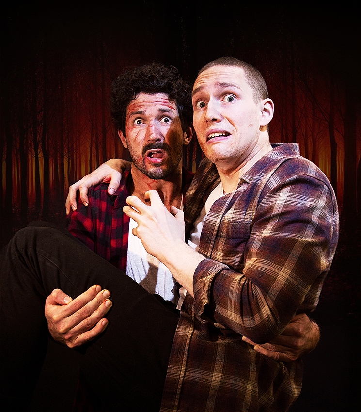 Two men dressed in flannel and white singlets look alarmed, holding each other dramatically. They stand in front of a dark red forest silhouette.