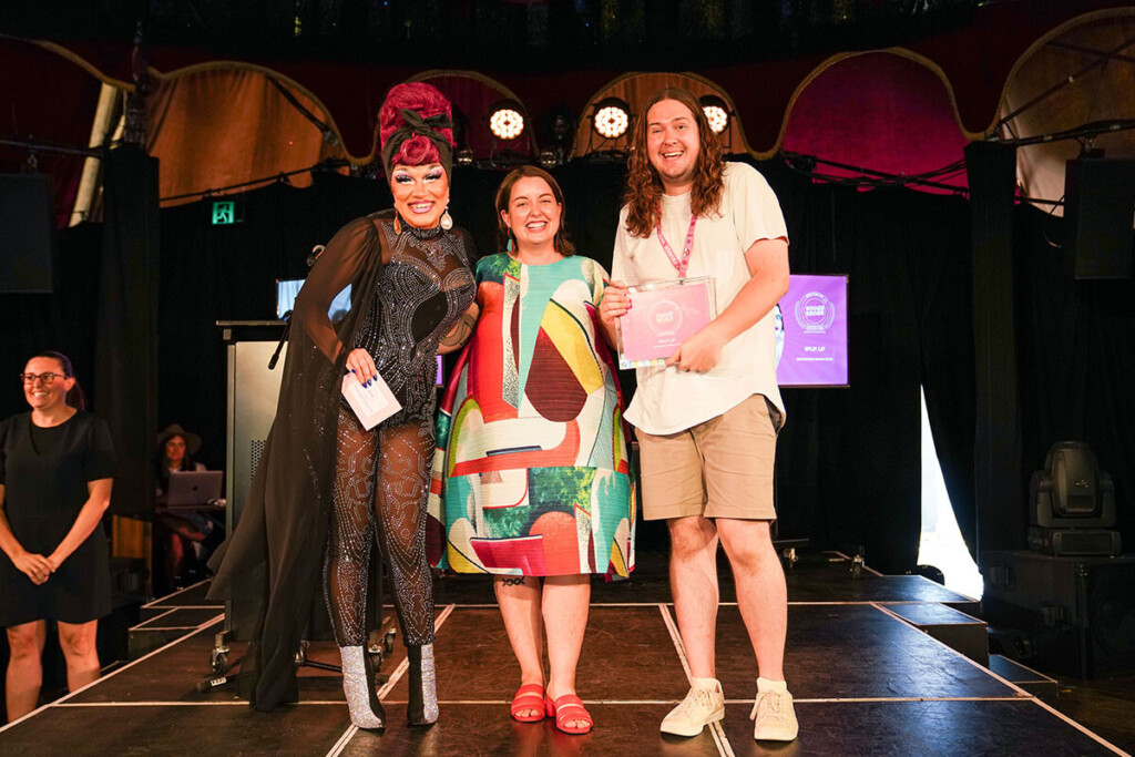 3 people standing on a stage holding an award