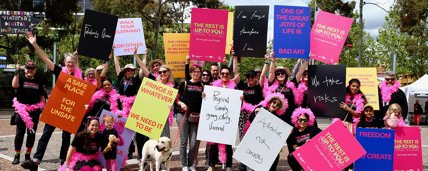 a group of people standing outdoors holding brightly coloured placards