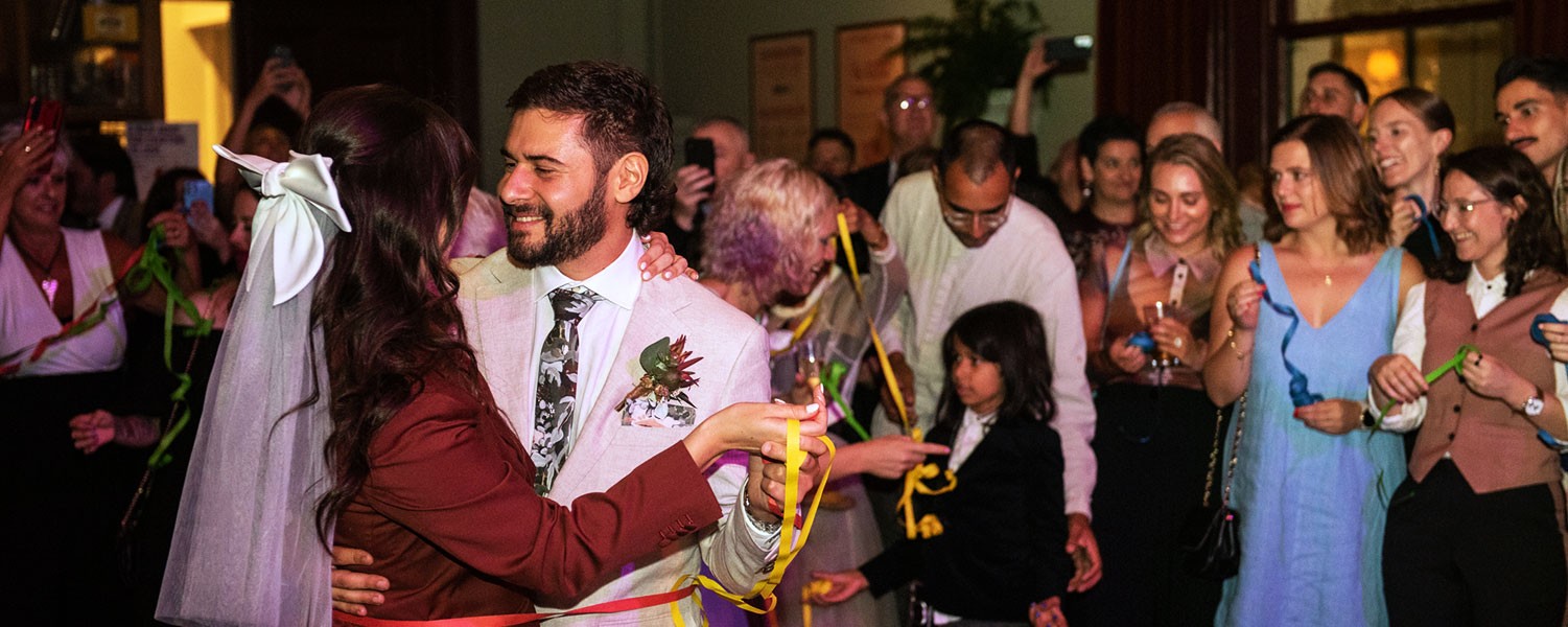 two newly weds dance infront of a crowd in the centre of a room